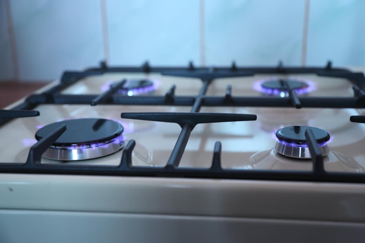 Four gas burners lit on a freestanding cooker