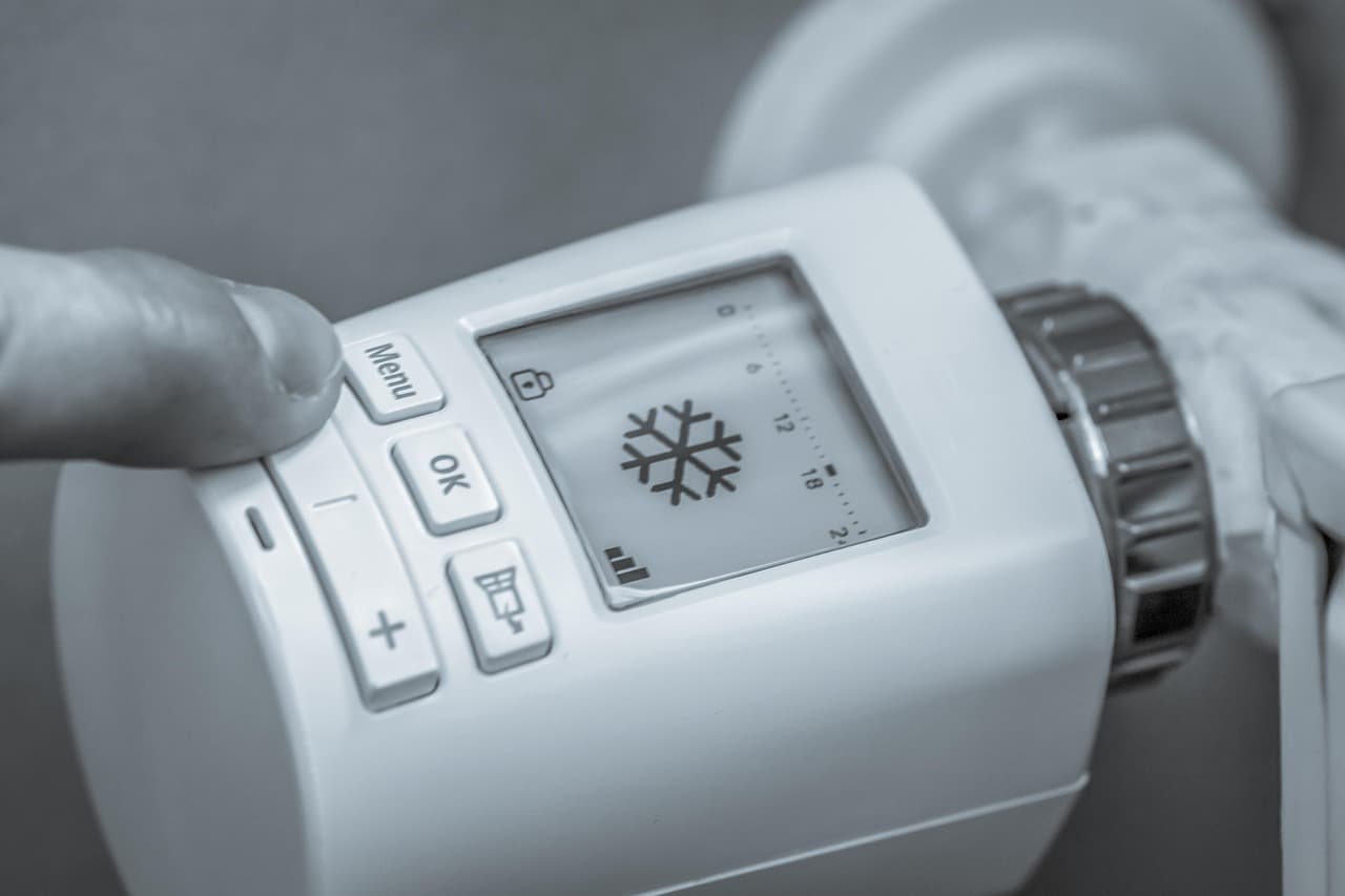 A hand setting a digital radiator thermostat